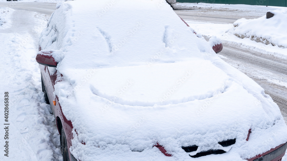 Fototapeta premium smile on a snow-covered car in the snow