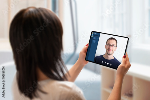 Video call on tablet concept. Work at home in virus epidemic. Woman holds a tablet and talks to a colleague.