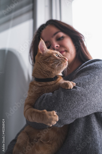 Pretty woman holding and looking at a cat