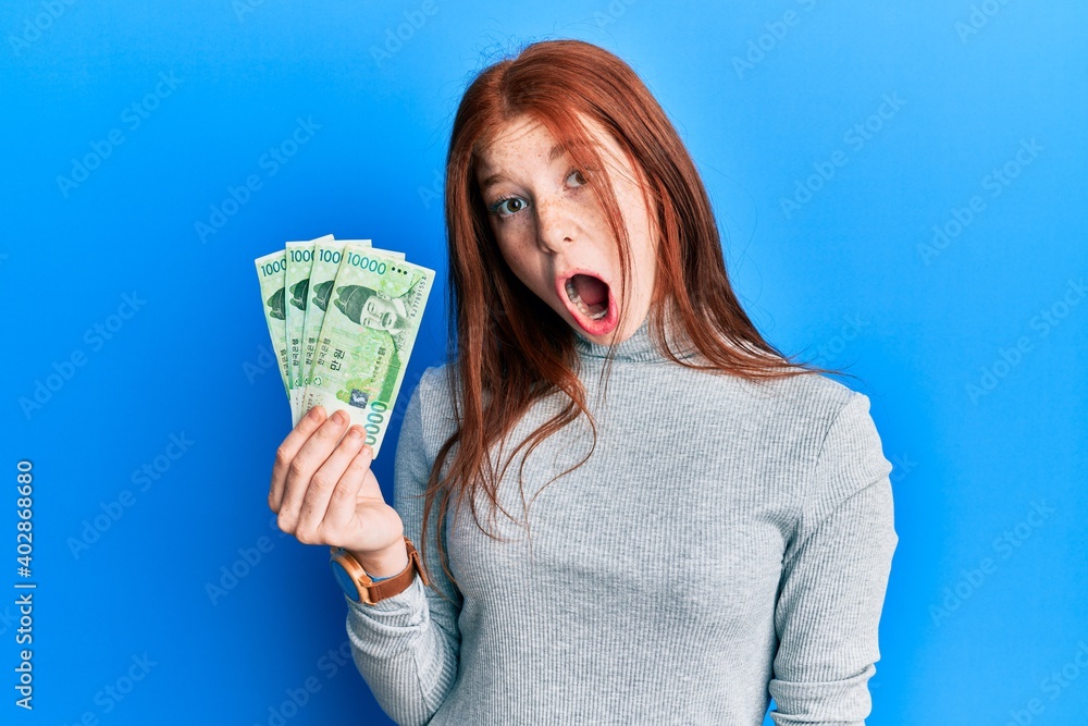 Ταπετσαρία Young red head girl holding 10000 south korean won banknotes scared and amazed w