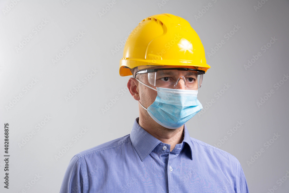 Young engineer worker wear a yellow helmet and medical mask. Coronavirus Hygiene, safety concept Young engineer worker wear a yellow helmet and medical mask. Coronavirus Hygiene, safety concept