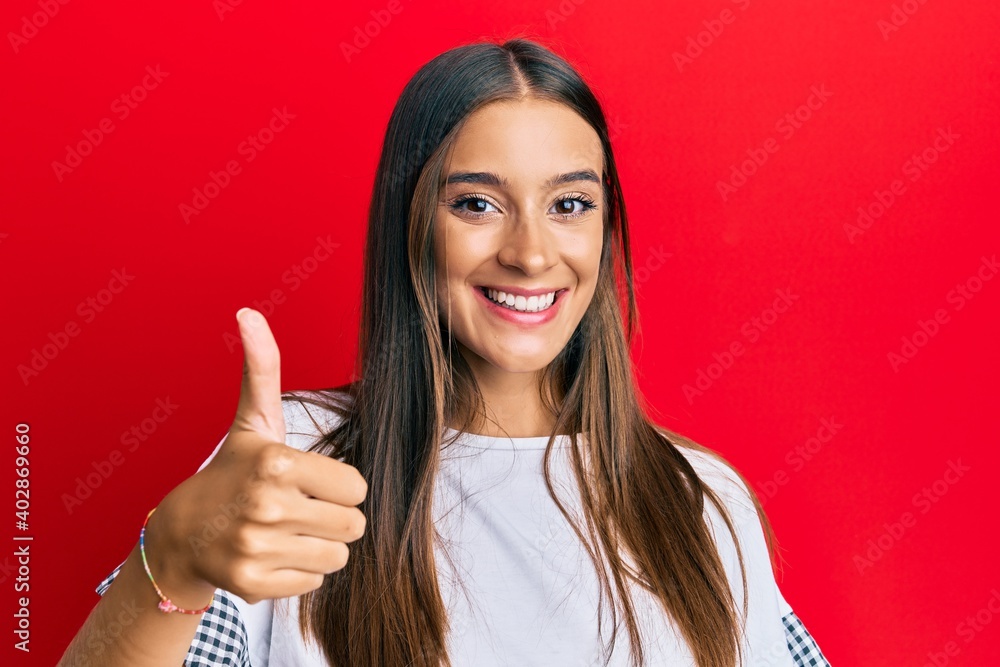 Young hispanic woman wearing casual clothes smiling happy and positive, thumb up doing excellent and approval sign Young hispanic woman wearing casual clothes smiling happy and positive, thumb up doing excellent and approval sign