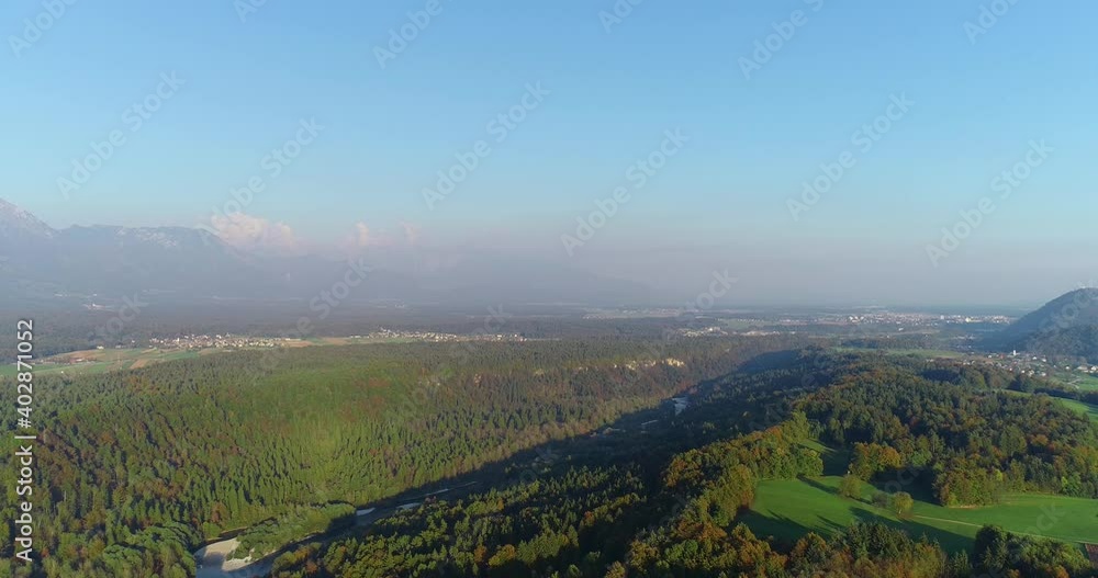 Amazing aerial view of Slovenia forest and Alps mountains in the distance. Colorful autumn season. Drone footage of vibrant woods. Sava river flowing in the valley. Descending Amazing aerial view of Slovenia forest and Alps mountains in the distance. Colorful autumn season. Drone footage of vibrant woods. Sava river flowing in the valley. Descending
