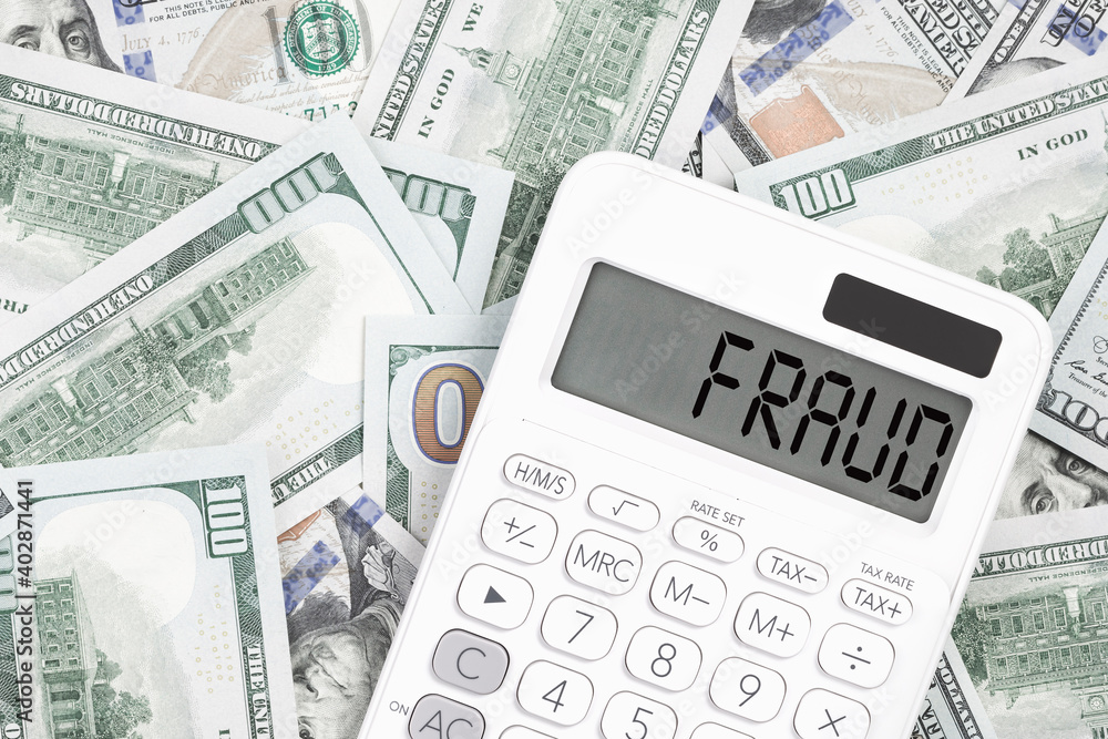 Fraud text on a calculator with us dollar money on the desk. Business and finance fraud prevention or identification concept. cashflow. Fraud text on a calculator with us dollar money on the desk. Business and finance fraud prevention or identification concept. cashflow.
