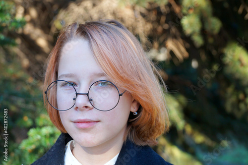 portrait of smiling teenage girl with blond hair wearing glasses