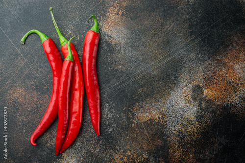 Whole red chili peppers, on old dark rustic background, top view or flat lay with copy space for text