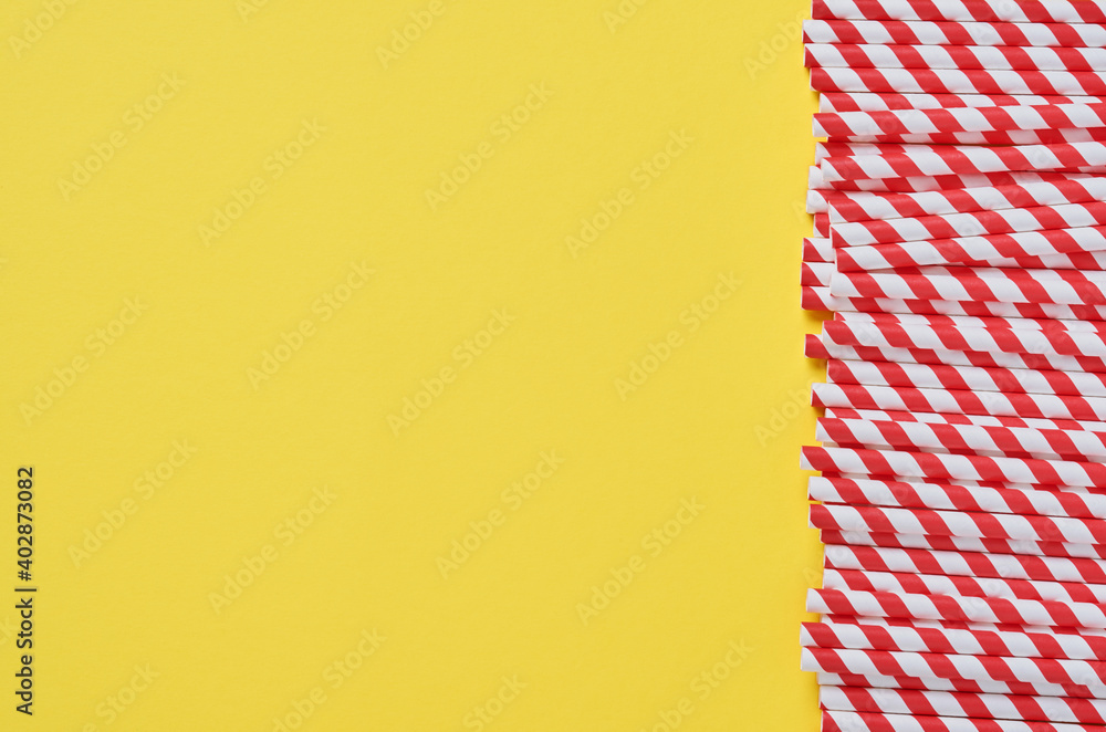 Fototapeta premium Drinking tubes made of red and brown paper and cornstarch, biodegradable material on yellow trend color 2021 background. Zero waste concept. Top view.