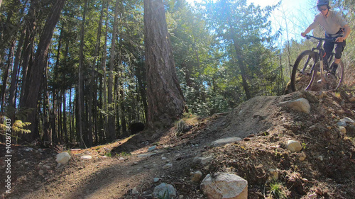 Young woman mountain biker rides a berm in the forest