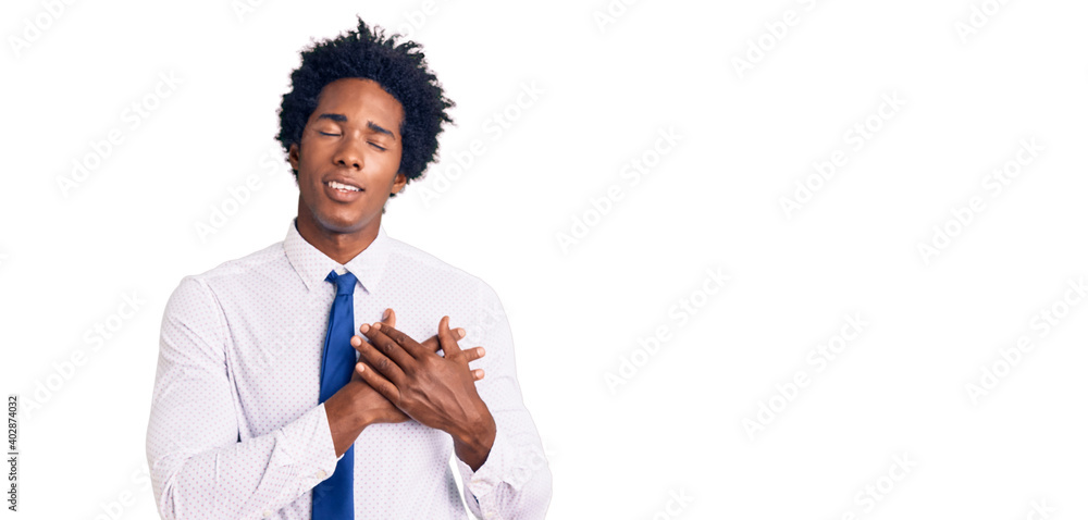 Handsome african american man with afro hair wearing business clothes smiling with hands on chest with closed eyes and grateful gesture on face. health concept. Handsome african american man with afro hair wearing business clothes smiling with hands on chest with closed eyes and grateful gesture on face. health concept.