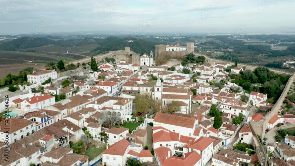 Scenic View Of White Houses, Red Tiled Roofs And Castle From Wall Of Fortress In Obidos Village, Portugal - aerial drone shot Scenic View Of White Houses, Red Tiled Roofs And Castle From Wall Of Fortress In Obidos Village, Portugal - aerial drone shot