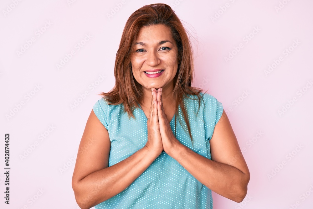 Middle age brunette hispanic woman wearing casual clothes praying with hands together asking for forgiveness smiling confident. Middle age brunette hispanic woman wearing casual clothes praying with hands together asking for forgiveness smiling confident.