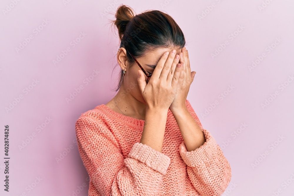 Young caucasian woman wearing casual clothes and glasses with sad expression covering face with hands while crying. depression concept.