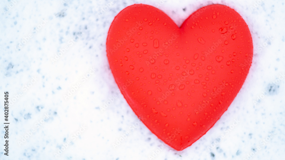 red heart with water drops on the snow