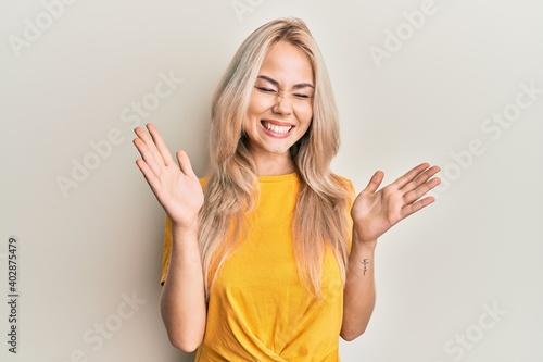 Wallpaper Mural Beautiful caucasian blonde girl wearing casual tshirt celebrating mad and crazy for success with arms raised and closed eyes screaming excited. winner concept Torontodigital.ca