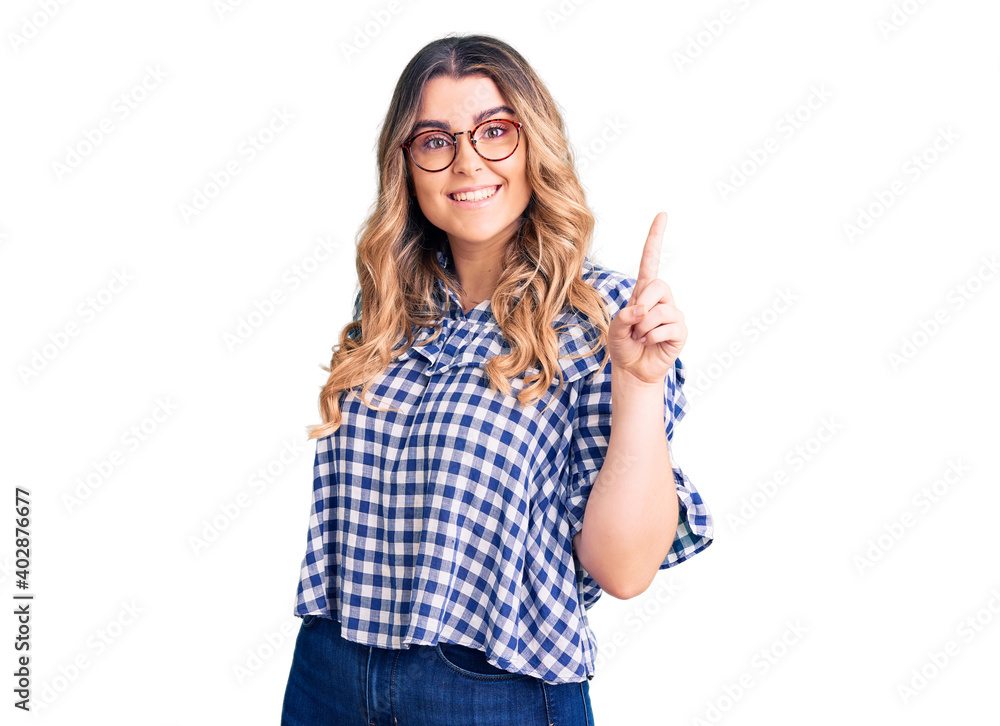 Young caucasian woman wearing casual clothes showing and pointing up with finger number one while smiling confident and happy. Young caucasian woman wearing casual clothes showing and pointing up with finger number one while smiling confident and happy.