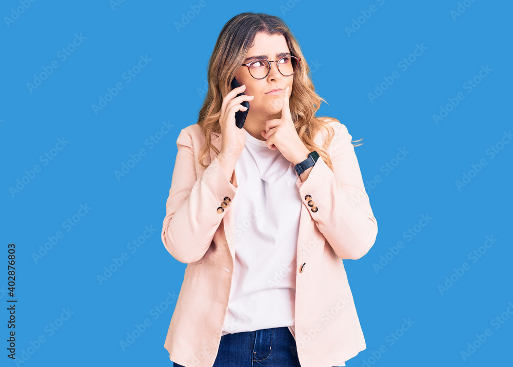 Young caucasian woman having conversation talking on the smartphone serious face thinking about question with hand on chin, thoughtful about confusing idea Young caucasian woman having conversation talking on the smartphone serious face thinking about question with hand on chin, thoughtful about confusing idea