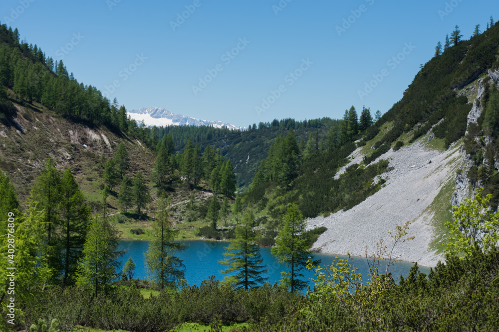 blue mountain lake with green trees while hiking