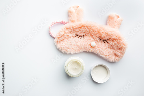 Cosmetic white containers with sleeping mask on white background top view. Skin night care products. Hand, face, body moisturizing cream jar.