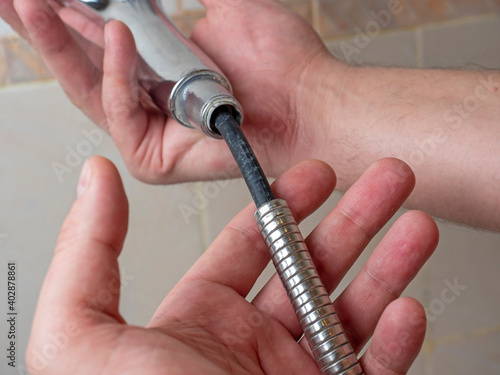 Broken chrome shower hose in men's hands. Rift, rubber, selective focus, shower equipment