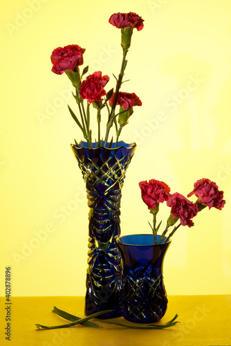 Blue vase with red flowers on a yellow background
