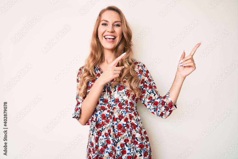 Young caucasian woman with blond hair wearing summer dress smiling and looking at the camera pointing with two hands and fingers to the side. Young caucasian woman with blond hair wearing summer dress smiling and looking at the camera pointing with two hands and fingers to the side.