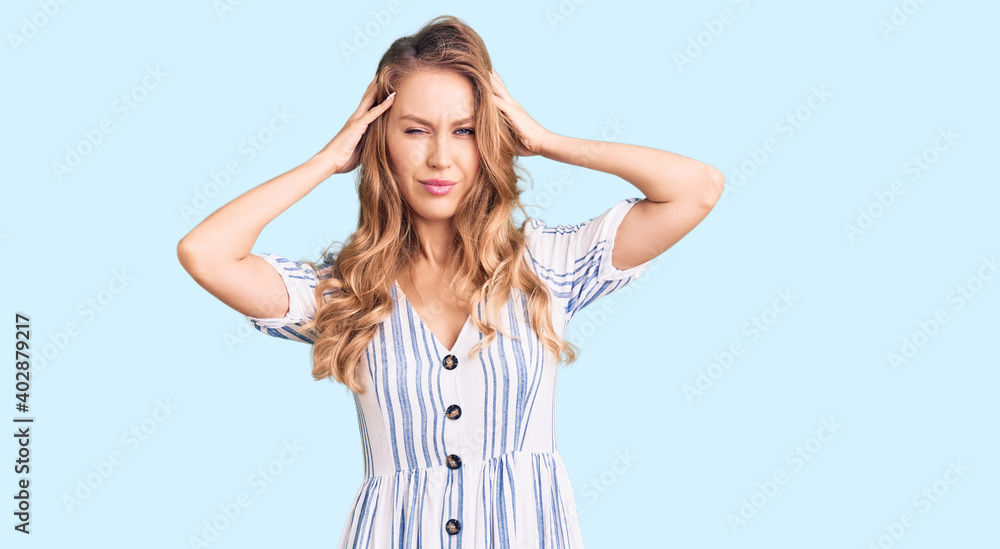 Young caucasian woman with blond hair wearing summer dress suffering from headache desperate and stressed because pain and migraine. hands on head. Young caucasian woman with blond hair wearing summer dress suffering from headache desperate and stressed because pain and migraine. hands on head.