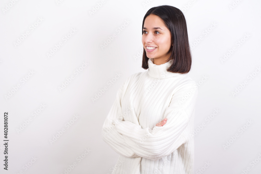 Young brunette woman wearing white knitted sweater against white background cross hands look copy space Young brunette woman wearing white knitted sweater against white background cross hands look copy space