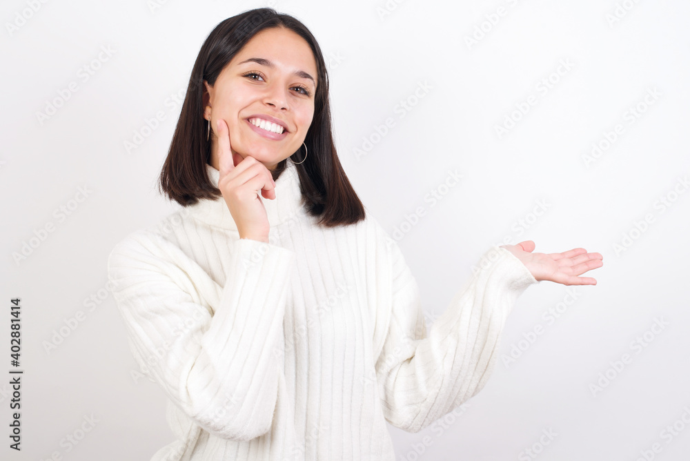 Funny Young brunette woman wearing white knitted sweater against white background hold open palm new product great proposition Funny Young brunette woman wearing white knitted sweater against white background hold open palm new product great proposition