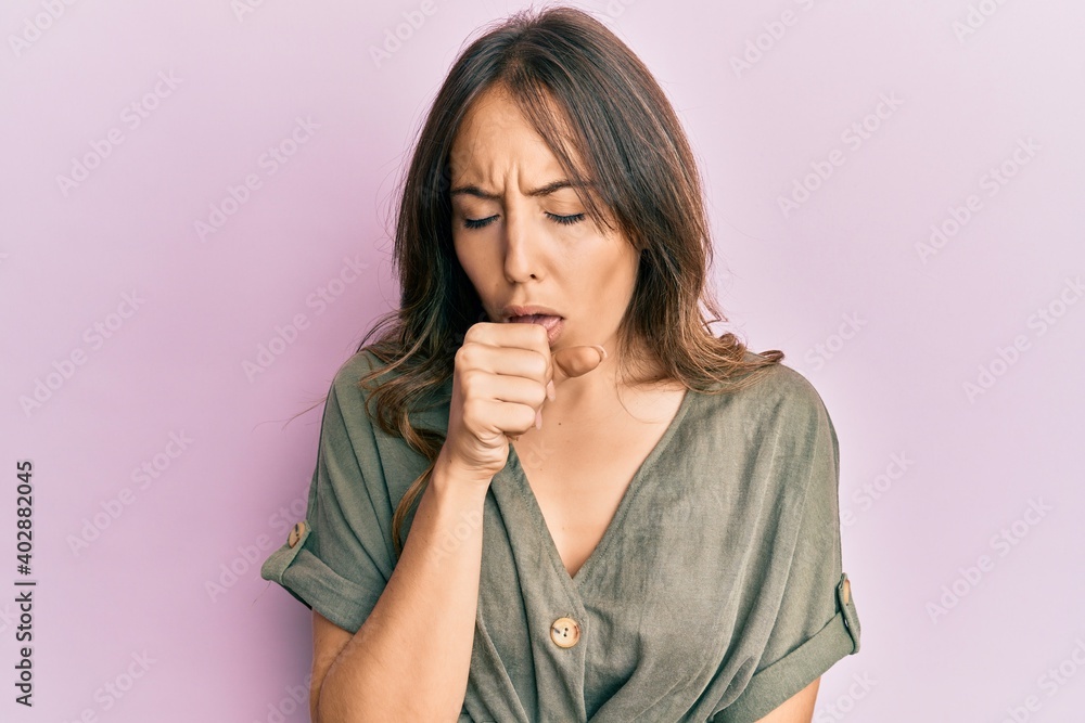 Young brunette woman wearing casual clothes feeling unwell and coughing as symptom for cold or bronchitis. health care concept. Young brunette woman wearing casual clothes feeling unwell and coughing as symptom for cold or bronchitis. health care concept.