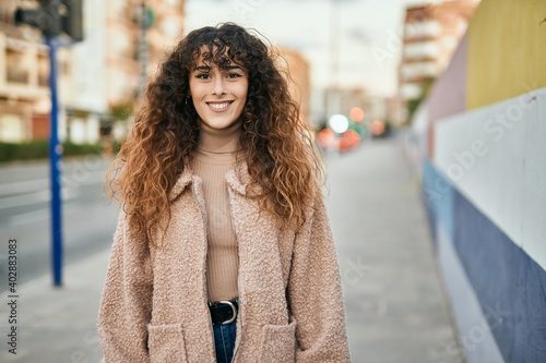 Young hispanic woman smiling happy standing at the city