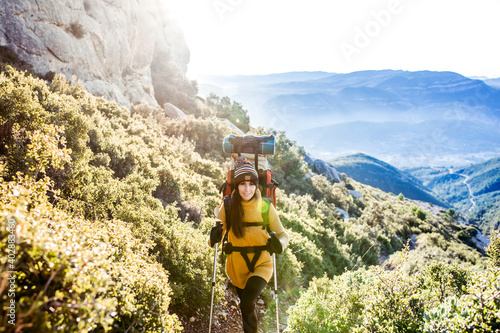 Happy hiking girl with a backpack ascends a mountain path. Travel lifestyle concept.