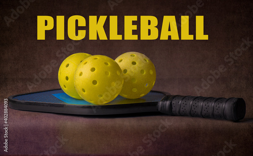 Pickleball paddle and balls. With the word "Pickleball" over a dark background. The sport of pickleball is America's fastest growing sport. © justasc