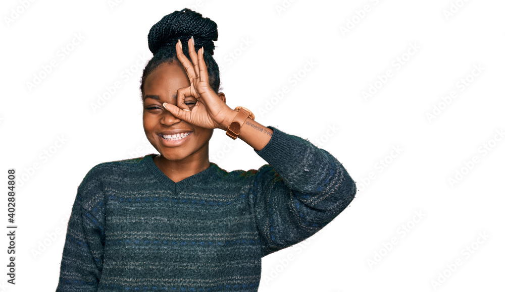 Young african american woman wearing casual clothes doing ok gesture with hand smiling, eye looking through fingers with happy face. Young african american woman wearing casual clothes doing ok gesture with hand smiling, eye looking through fingers with happy face.