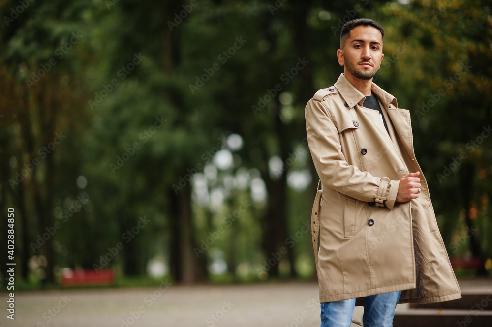 Stylish kuwaiti man at trench coat walking at park. Stylish kuwaiti man at trench coat walking at park.