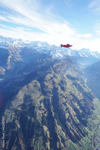 Wingsuit flier glides over snowcapped mountains