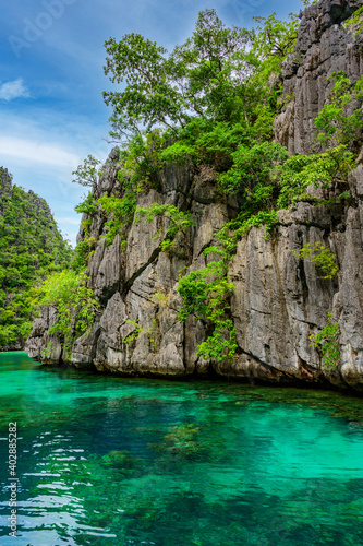 Blue crystal water in paradise Bay with boats on the wooden pier at Kayangan Lake in Coron island, tropical travel destination - Palawan, Philippines.