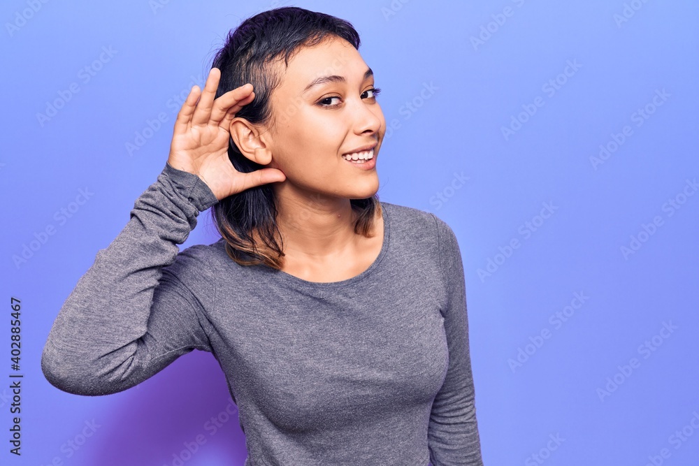 Young woman wearing casual clothes smiling with hand over ear listening and hearing to rumor or gossip. deafness concept. Young woman wearing casual clothes smiling with hand over ear listening and hearing to rumor or gossip. deafness concept.