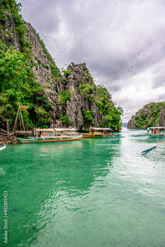 Blue crystal water in paradise Bay with boats on the wooden pier at Kayangan Lake in Coron island, tropical travel destination - Palawan, Philippines. photo