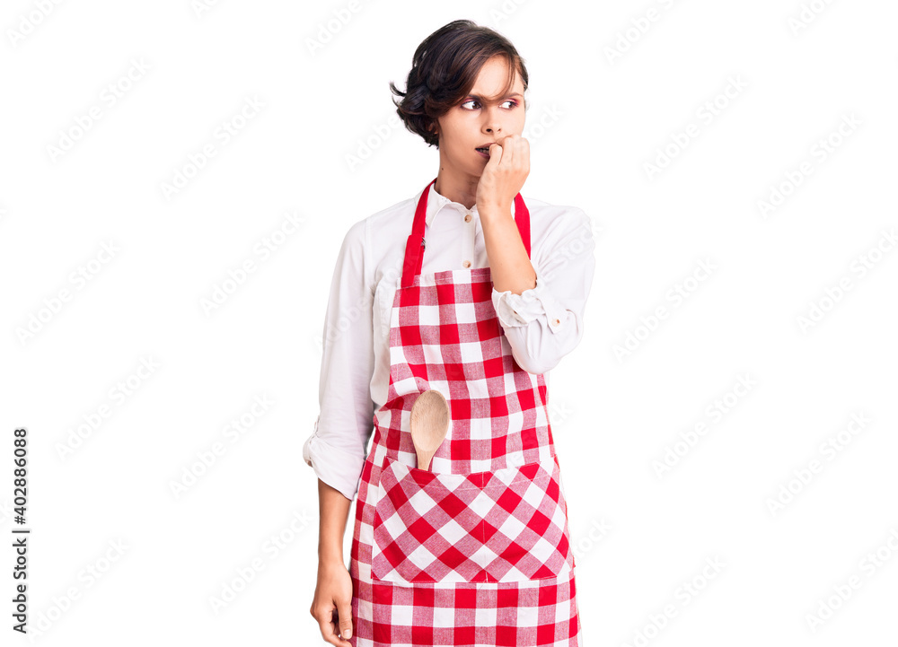 Beautiful young woman with short hair wearing professional cook apron looking stressed and nervous with hands on mouth biting nails. anxiety problem. Beautiful young woman with short hair wearing professional cook apron looking stressed and nervous with hands on mouth biting nails. anxiety problem.