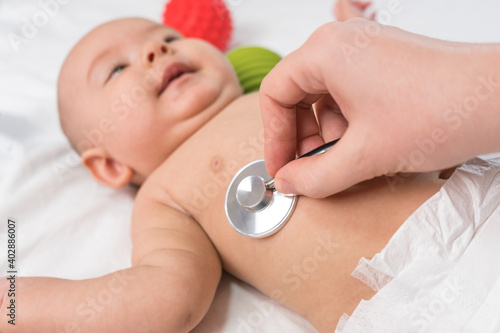 Doctor's hands hold a stethoscope and listen to the heart of a newborn. Selective focus