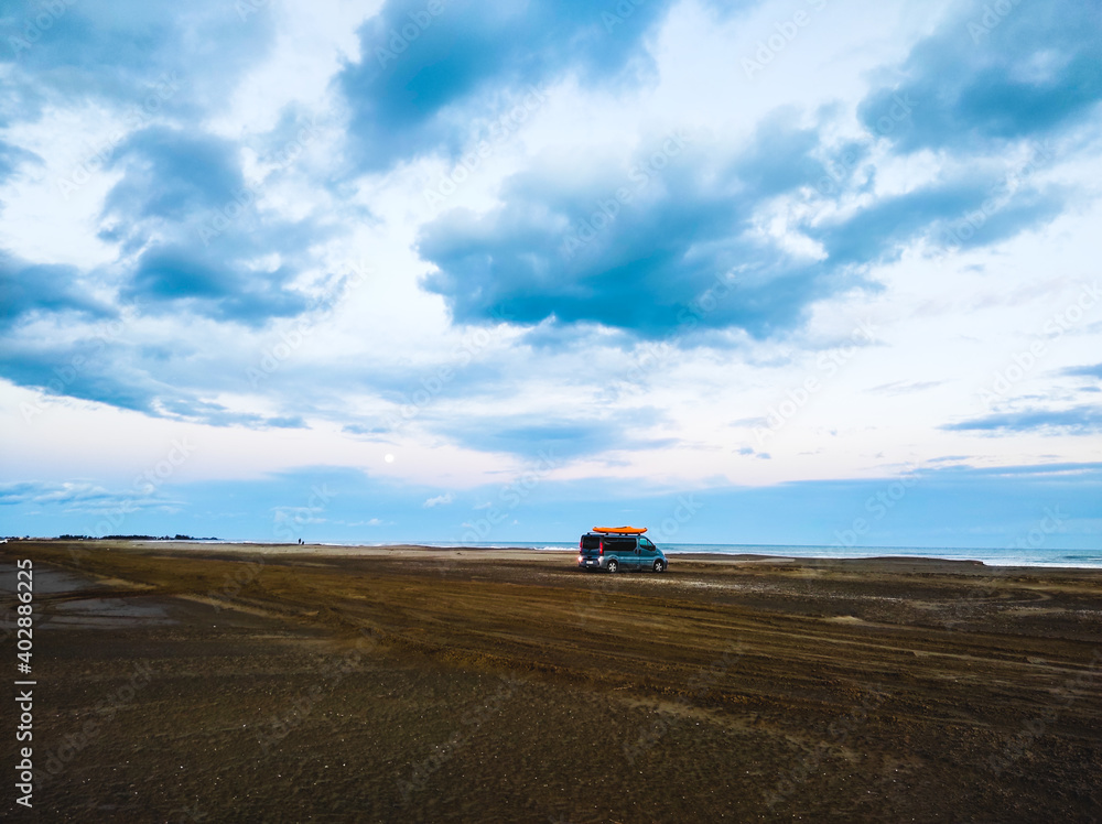 beach with cloudy sky and van with kayak
