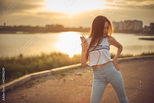 Young beautiful caucasian girl listening to music with smartphone walking in the city with headphones smiling - relax, youth, emancipation concept photo