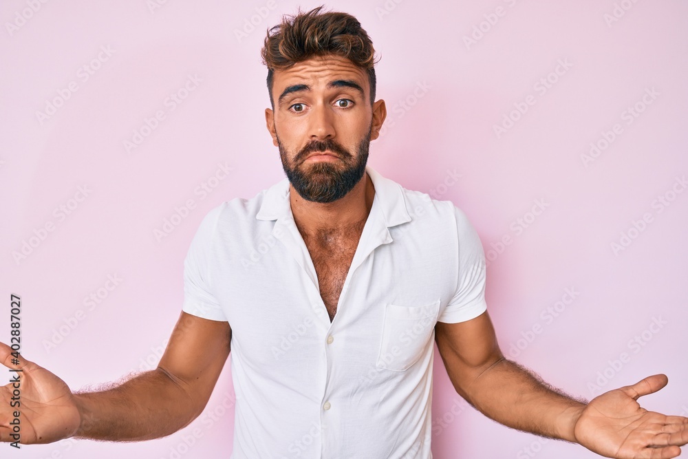 Young hispanic man wearing casual clothes clueless and confused expression with arms and hands raised. doubt concept. Young hispanic man wearing casual clothes clueless and confused expression with arms and hands raised. doubt concept.