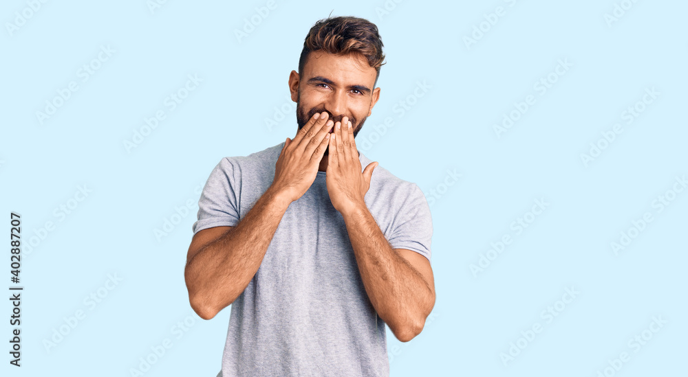 Young hispanic man wearing casual clothes laughing and embarrassed giggle covering mouth with hands, gossip and scandal concept Young hispanic man wearing casual clothes laughing and embarrassed giggle covering mouth with hands, gossip and scandal concept