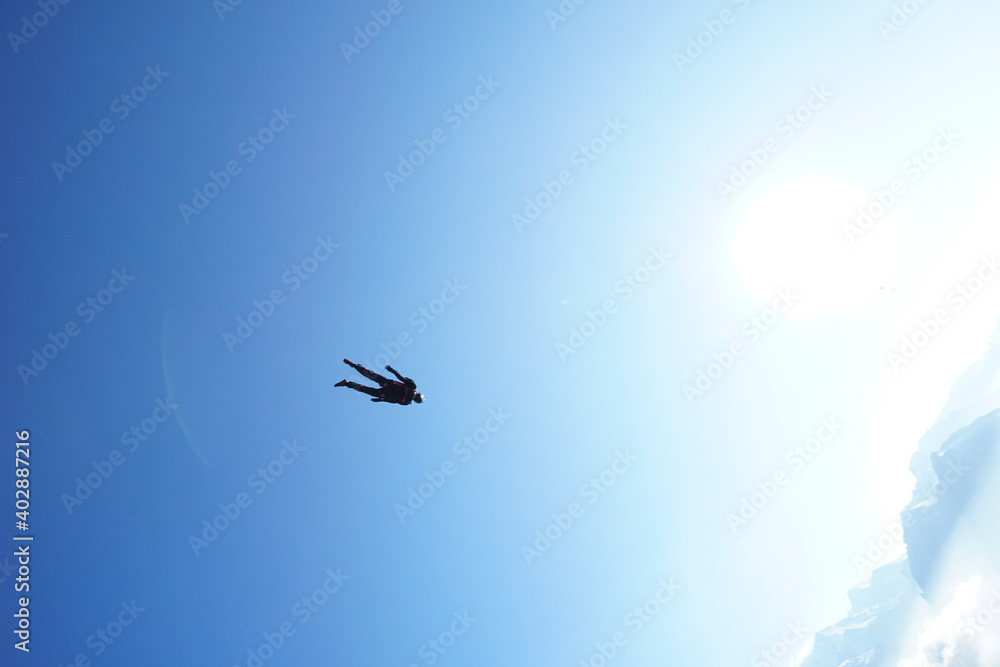 Man glides in tracking suit above mountains Man glides in tracking suit above mountains