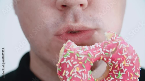 The man bites and eats a donut. Quick snack, excess cholesterol. Close-up. photo