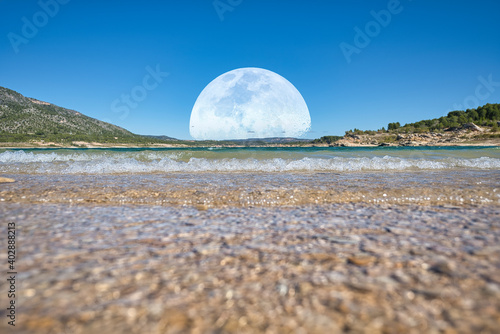 saliendo la luna sobre las montañas y el agua 