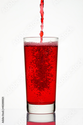 Pouring red juice into a glass against a light background. Dynamic shot