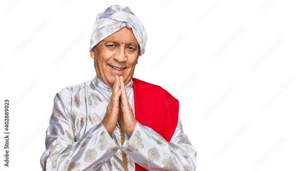 Senior hispanic man wearing tradition sherwani saree clothes praying with hands together asking for forgiveness smiling confident. Senior hispanic man wearing tradition sherwani saree clothes praying with hands together asking for forgiveness smiling confident.