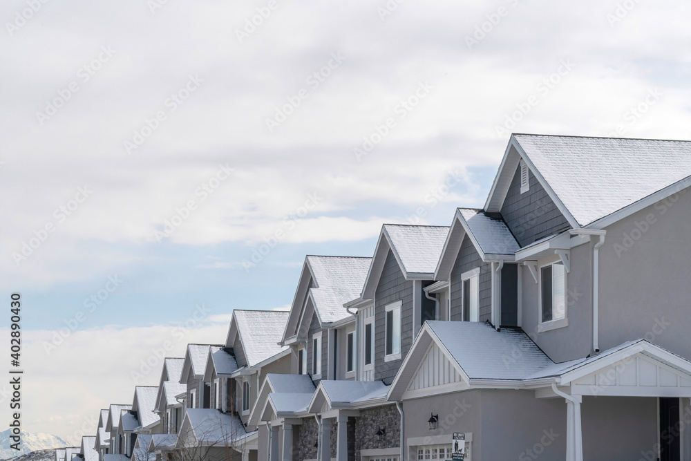 Townhouses with snowy gable roofs in winter on a scenic suburbs community. - obrazy, fototapety, plakaty 